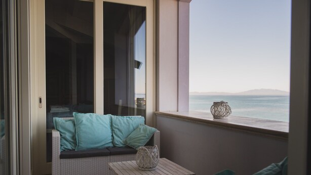 A balcony with a wicker sofa, a small table, and a decorative lantern. - VILLA LILLA penthouse on the beach of San Vincenzo Tuscany luxury (San Vincenzo)