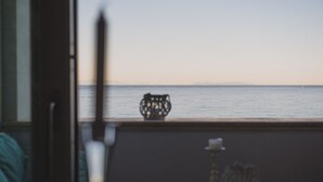 A balcony with a view of the sea, a table with a candle and a glass, and a chair. - VILLA LILLA penthouse on the beach of San Vincenzo Tuscany luxury (San Vincenzo)