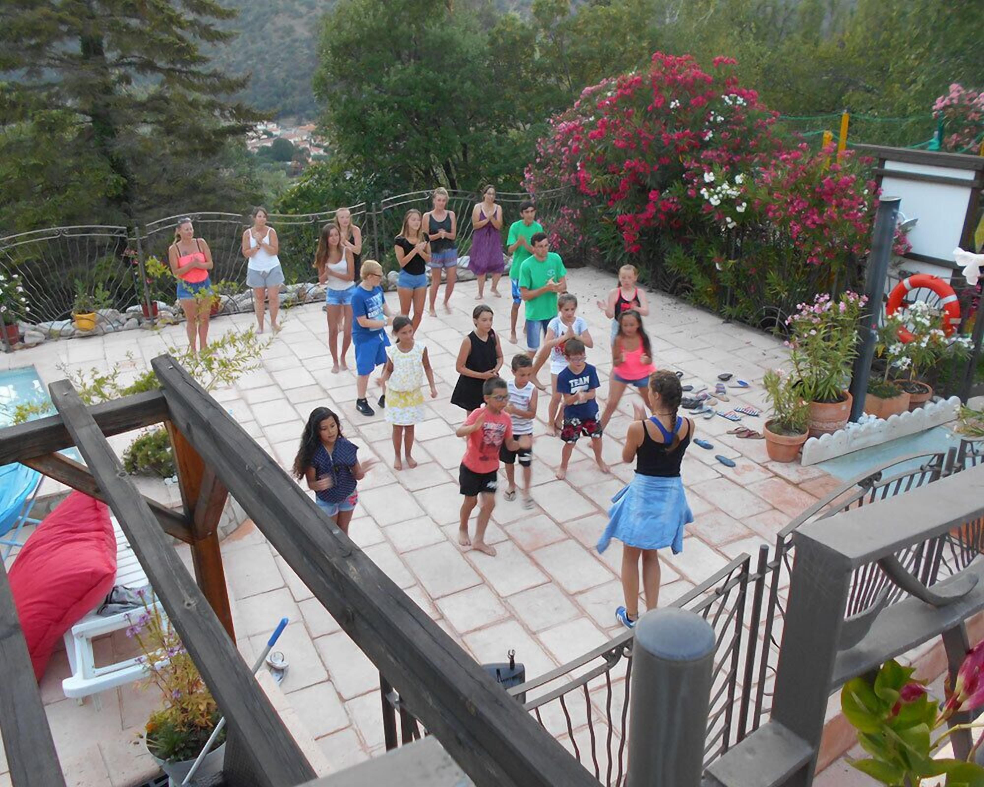 A group of people gathered on a patio with a pool and potted plants.