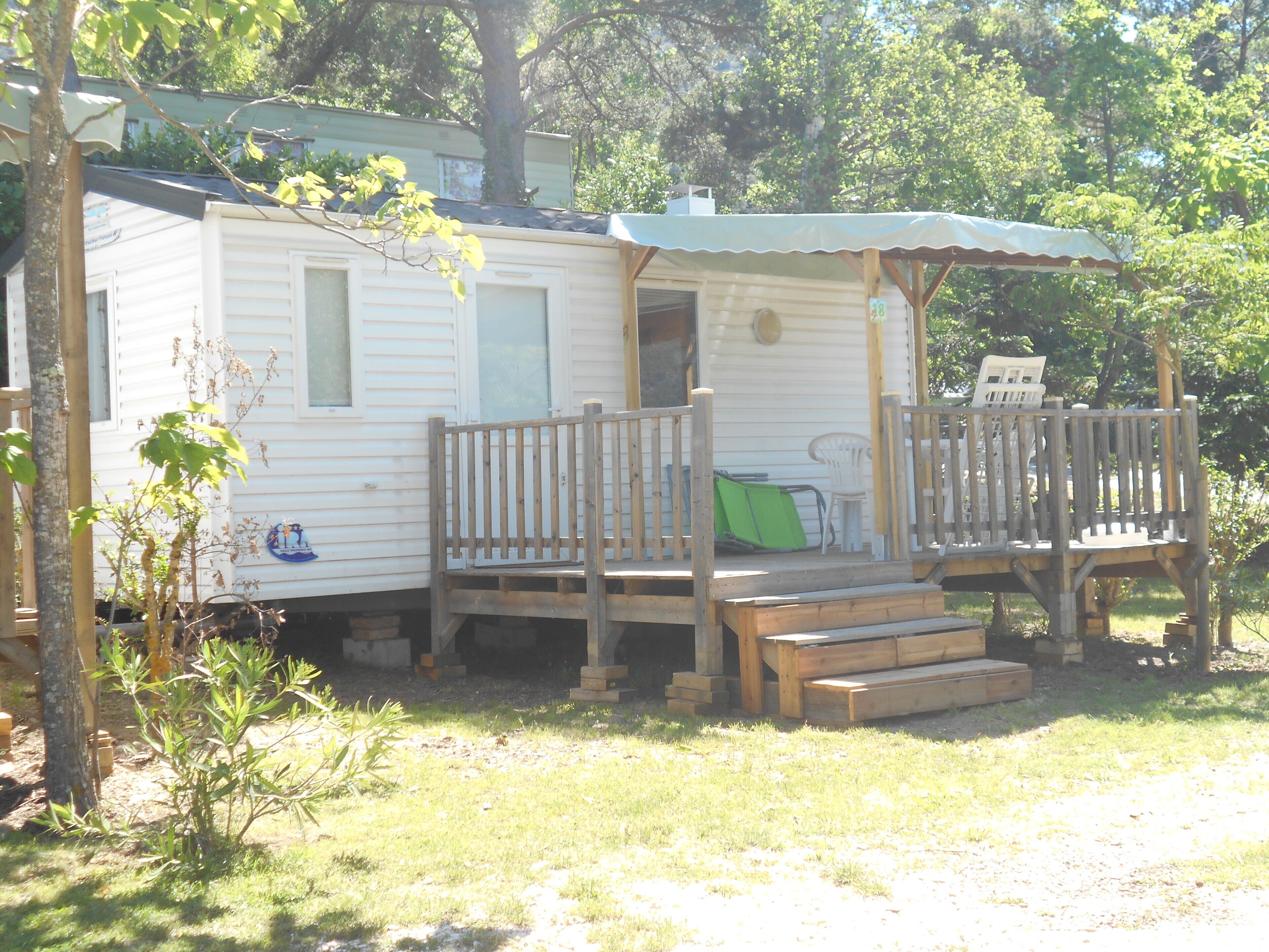 A mobile home with a porch and a covered seating area.