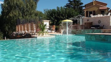 Una piscina al aire libre de temporada, sombrillas