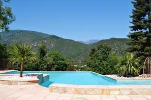 A swimming pool with a view of green hills and a clear sky. - Camping Bellevue (Ria-Sirach)