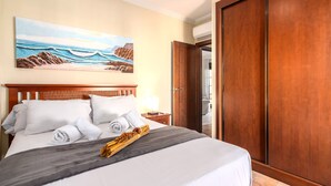 Ein Hotelzimmer mit einem großen Bett, einem Meeresbild an der Wand und einem hölzernen Kleiderschrank.