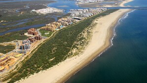 Eine Luftaufnahme einer Küstenstadt mit langem Strand, dichter Bebauung und einem Flussdelta.