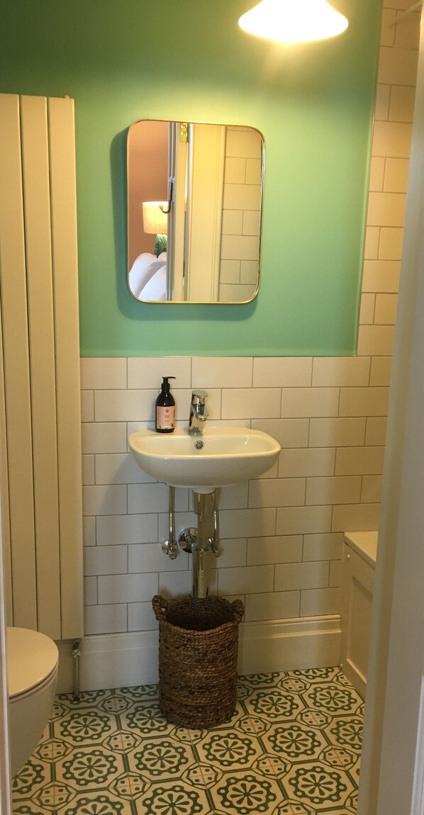 A bathroom with a white sink, a mirror, and a patterned floor. - Number 6 Narrow Water Castle (Warrenpoint)
