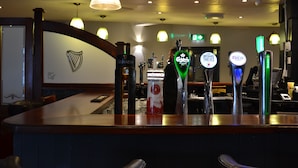 Zona de bar con múltiples grifos de cerveza, una barra y un logotipo en la pared.