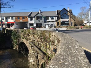 Un pont de pierre enjambe une rivière, avec des bâtiments de chaque côté, notamment un bar et un restaurant.