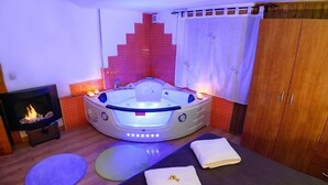 Une salle de spa équipée d’un bain à remous chauffé, d’une table de massage et d’une cheminée.