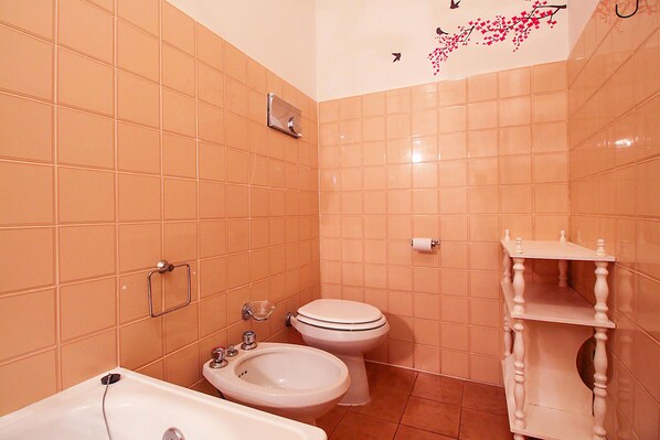 A bathroom with a bathtub, two toilets, a sink, and a vanity with a mirror. - Apartment Talamone at 200 m from the sea (Talamone)
