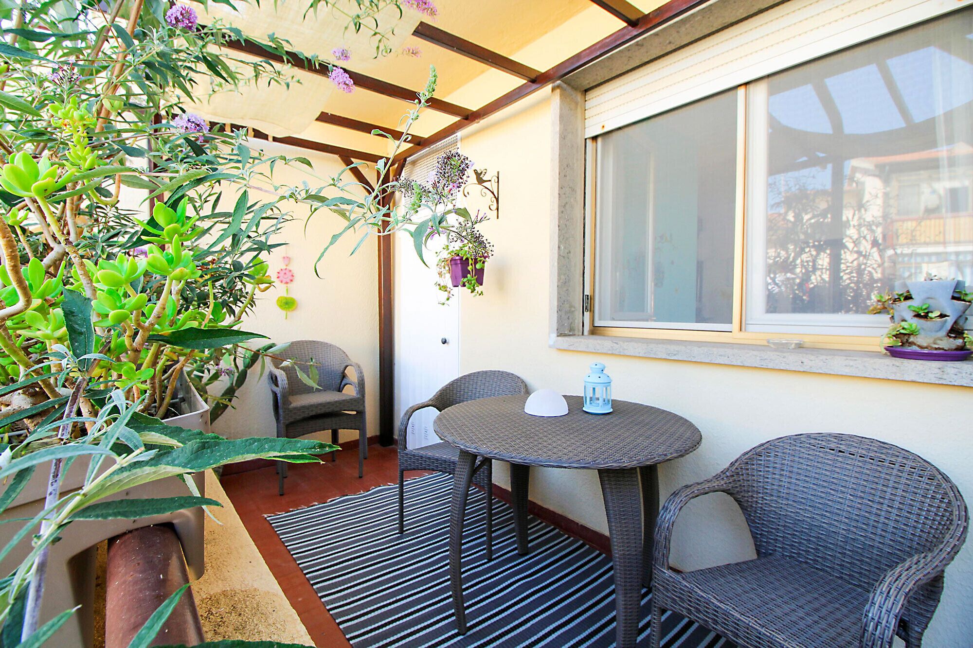 A patio area with wicker furniture, a round table, and potted plants.