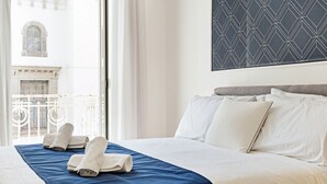 Une chambre d’hôtel avec un lit, des oreillers blancs, une couvre-lit bleue et une vue sur un immeuble par la fenêtre.