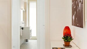 Un couloir menant à une salle de bain avec un lavabo et une serviette blancs.