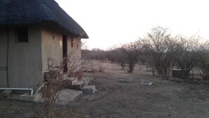 A rustic building with a thatched roof, a small window, and a concrete pathway leading to it. - Pop Lamont Camp (Ngoma)