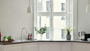 Cucina completamente attrezzata con pensili bianchi, un piano di lavoro in legno e una finestra che lascia entrare la luce naturale.