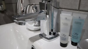 Un lavabo de salle de bain avec un robinet chromé, un distributeur de savon et deux flacons de savon pour les mains.