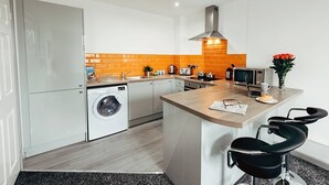 Une cuisine moderne équipée d’un lave-linge, d’un four à micro-ondes et d’une machine à café.