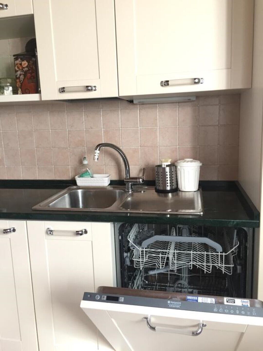 Eine kleine Küche mit Geschirrspüler, Spüle und Kaffeemaschine.