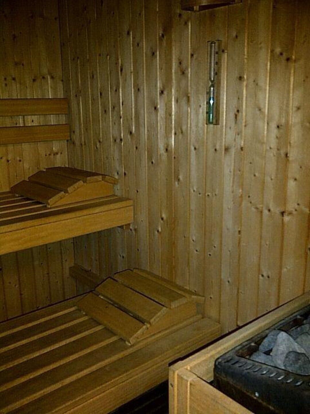 A sauna room with wooden benches and a stone bench.