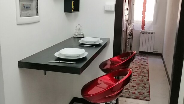 A modern kitchen with a black countertop, white plates, and red bar stools. - Exclusive apartment with terrace (Padova)