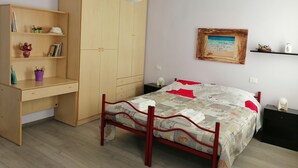 A bedroom with a bed, a wooden wardrobe, a desk, and a shelf with books and decorative items. - Exclusive apartment with terrace (Padova)