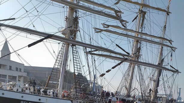 Un gran barco velero llamado BELEM atracado en un puerto con un muro de piedra al frente.