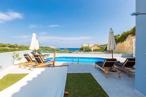 Una piscina al aire libre, sillones reclinables de piscina
