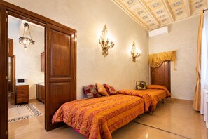 A bedroom with a double bed, a wardrobe, a bedside table, a lamp, and a ceiling with floral patterns.