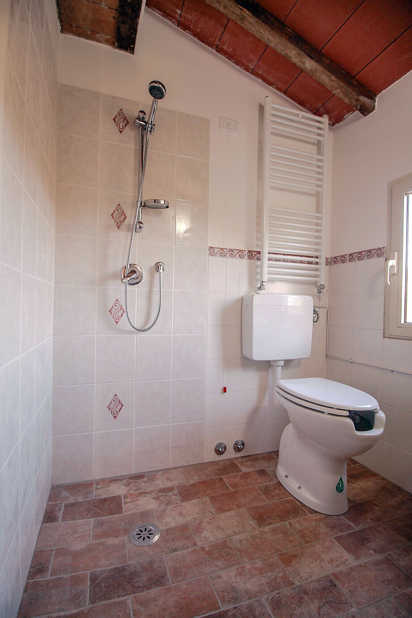 Een badkamer met douche, toilet en betegelde wanden.