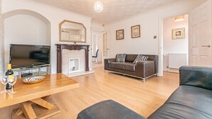 A living room with a television, a fireplace, a sofa, and a dining table.