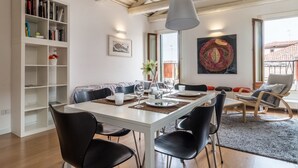 Un espace repas avec une table blanche, des chaises noires et un luminaire suspendu.
