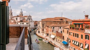 Un canal à Venise, avec des bâtiments de chaque côté, un bateau sur l’eau et un pont au premier plan.