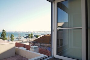 Enjoy breathtaking views of the water from this balcony with a clear view of a distant bridge.