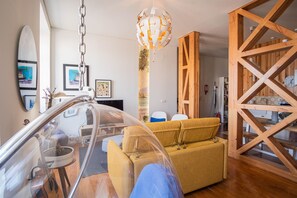 Relax in this stylish living room with a clear glass partition, wooden trestle structure, and comfortable sofa.