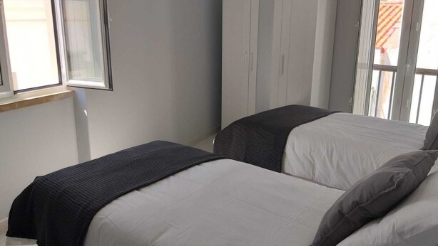A bedroom with two beds, a window, and a wardrobe. - Renovated apartment right in the city center (Lagos)