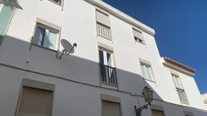 A white building with multiple windows, a satellite dish, and a street lamp. - Renovated apartment right in the city center (Lagos)