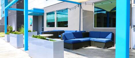 Un espacio al aire libre con mobiliario azul y blanco, jardineras y un edificio con decoración azul y blanca.