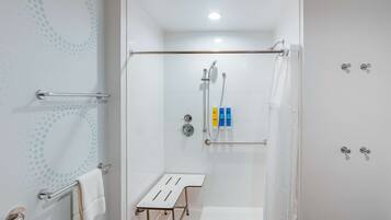 A modern shower area with a glass door, a towel rack, a shower control panel, and a small table.