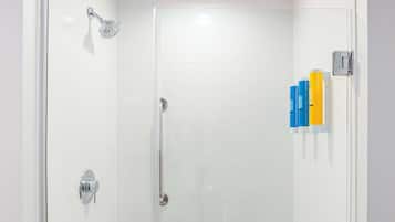 A glass-enclosed shower with a handheld showerhead, a glass door, and a towel rack with a towel.