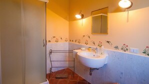 A bathroom with a white sink, a mirror, and a towel rack. - B&B immersed in the Green (Nicolosi)