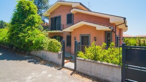 A two-story house with a balcony, a gated entrance, and a well-maintained garden. - B&B immersed in the Green (Nicolosi)