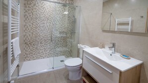 A modern bathroom with a glass-enclosed shower, a white toilet, and a white sink with a mirror above. - La Fontina de Luarca (Luarca)