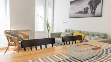 A modern living room with a grey sofa, two black chairs, a wooden coffee table, and a striped rug.