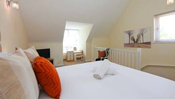 A bedroom with a bed, a desk, a chair, a window, and a painting on the wall.
