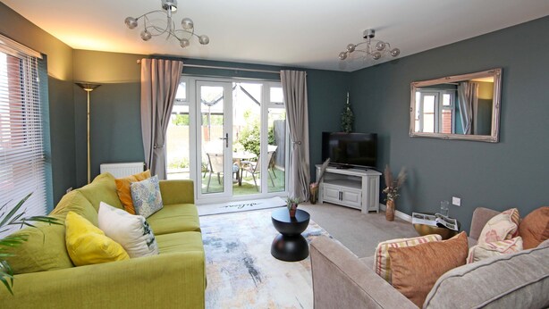 A living room with a sofa, a coffee table, a television, and a large window. - Autumn Heights Apartments (Telford)