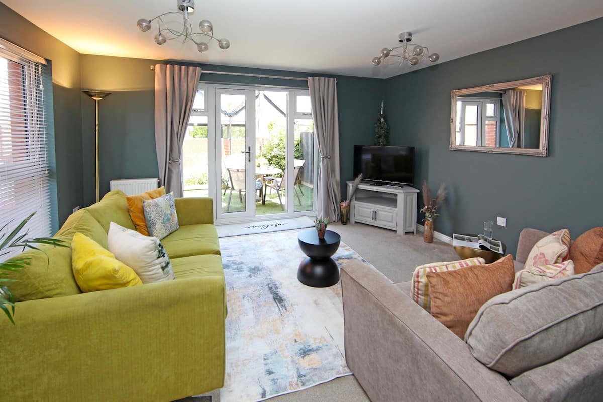 A living room with a sofa, a coffee table, a television, and a large window.