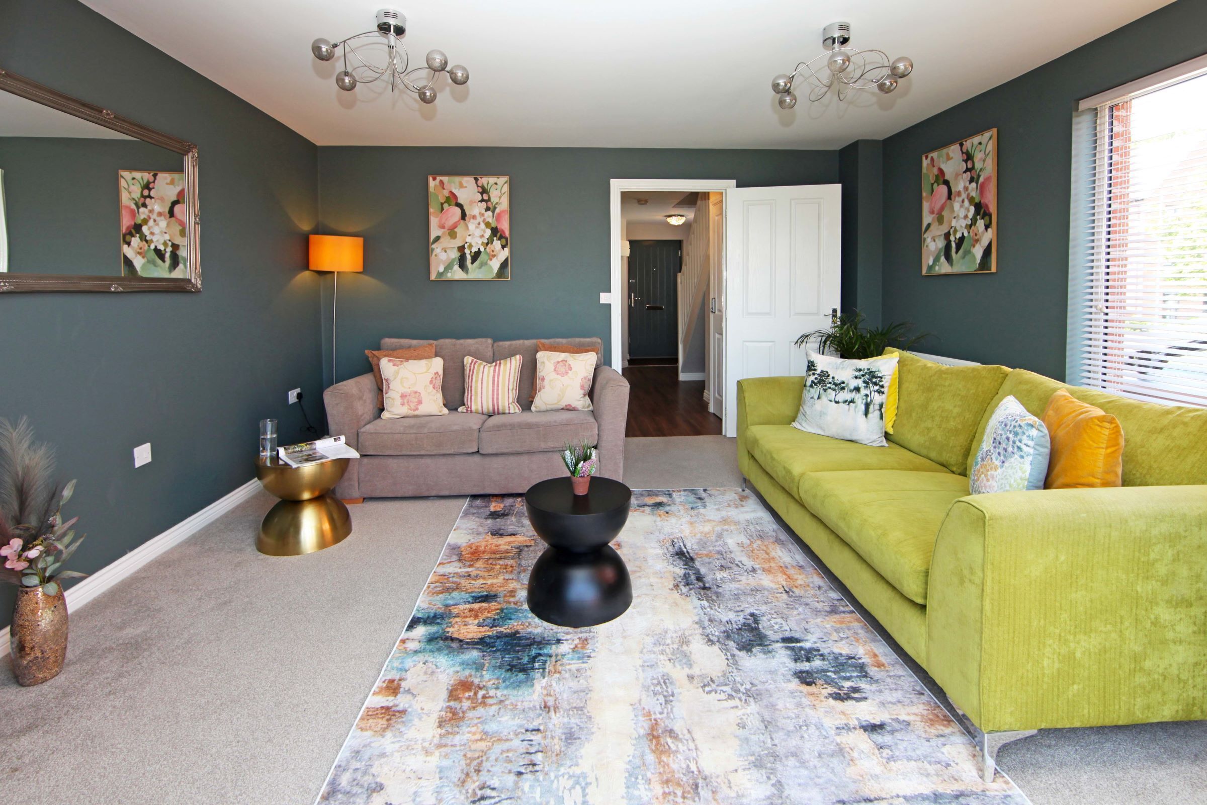 A living room with a green sofa, a brown sofa, a black coffee table, and a colorful rug.