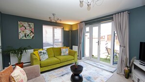 Una sala de estar con un sofá verde, una mesa de centro negra y un mueble para televisión.