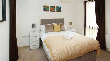 A bedroom with a bed, two bedside tables, a nightstand, a dresser, and a window with curtains.