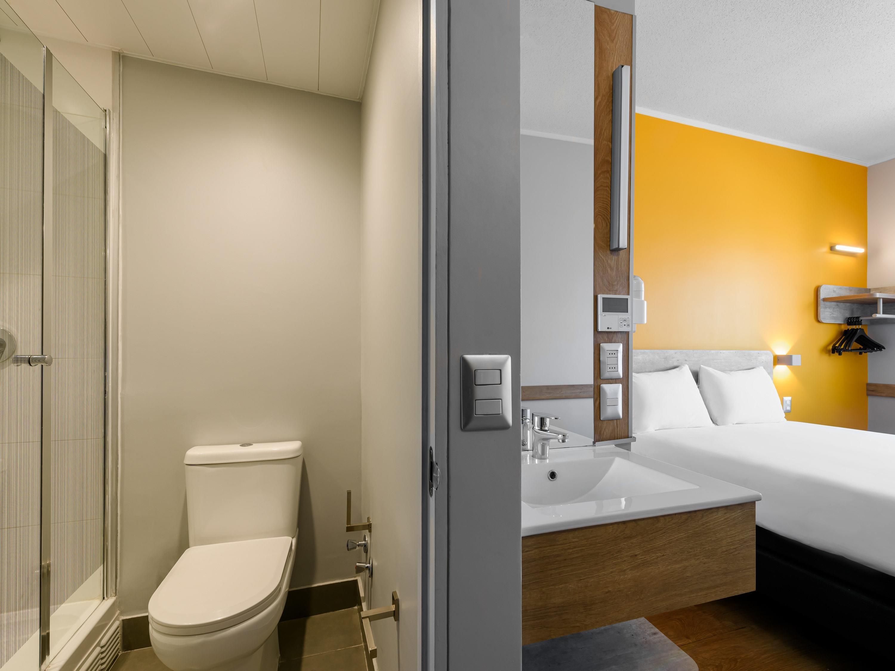 A modern bathroom with a toilet, shower, and sink.