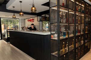 Una zona de bar con un cantinero, una barra y estantes llenos de botellas de licor.